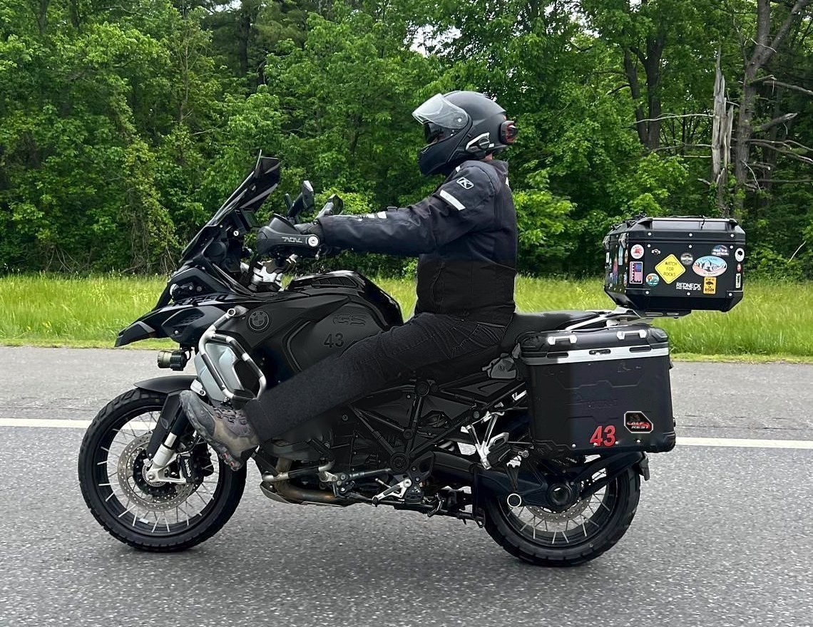 Rider on a black BMW R1250 GS Adventure at highway speed with legs stretched forward onto Calf Rests